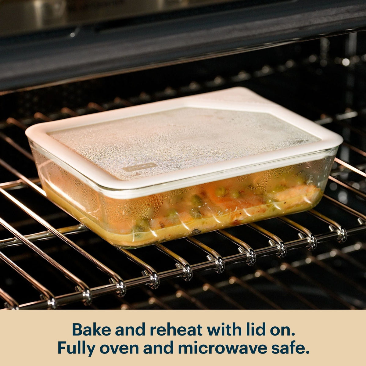 Pyrex glass container with a clear lid reheating food in an oven.