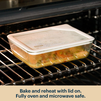 Pyrex glass container with a clear lid reheating food in an oven.