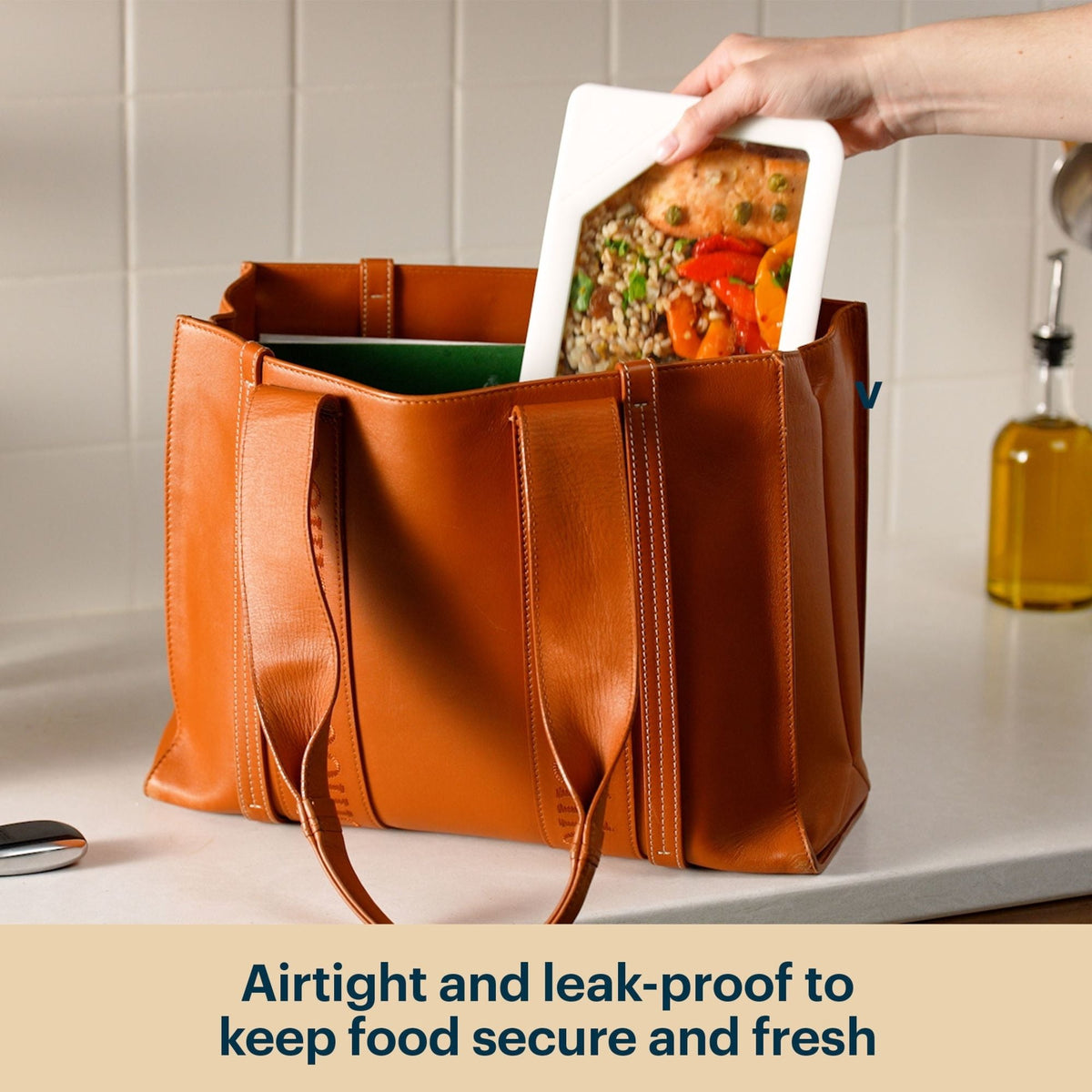 Glass food container with clear lid inside a tote bag.