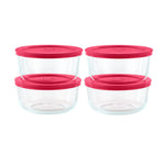 Set of four clear glass food storage containers with pink lids on a white background